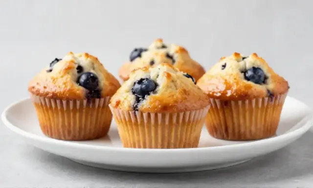Vier saftige Blaubeermuffins, perfekt gebacken im Philips Airfryer, auf einem weißen Teller.