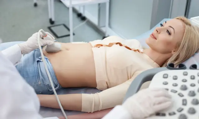 Kobieta leży na kozetce, a lekarz wykonuje jej cystografię mikcyjną, badając pęcherz moczowy.