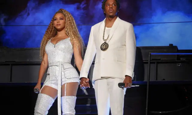 Beyoncé i Jay-Z, symbol sukcesu i majątku, na scenie w błyszczących strojach.
