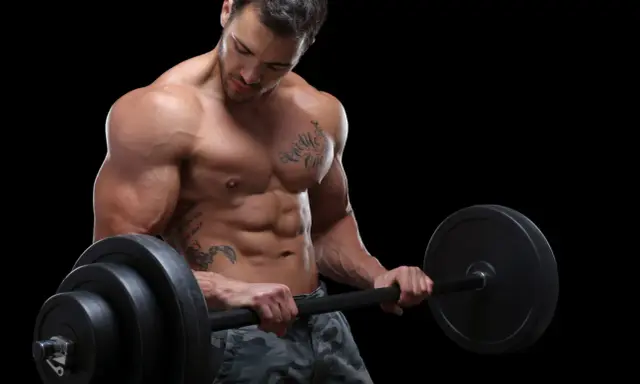 Ein muskulöser Mann mit Tattoos hebt eine Langhantel. Sein Sixpack ist deutlich sichtbar, ein Zeichen für seinen Powerlifting Trainingsplan.