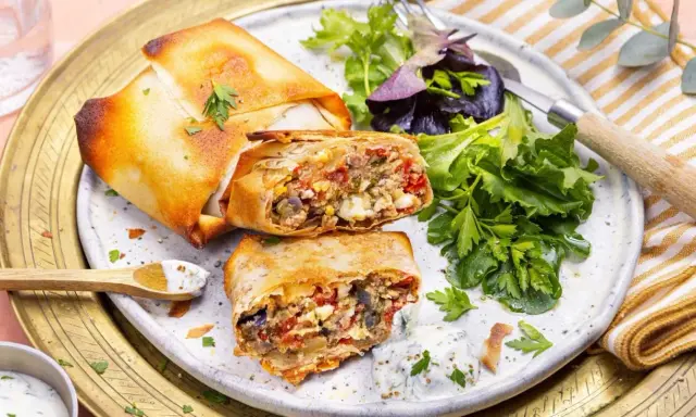 Deux bricks au thon croustillantes, garnies d'une farce savoureuse, servies avec une salade fraîche et une sauce crémeuse.