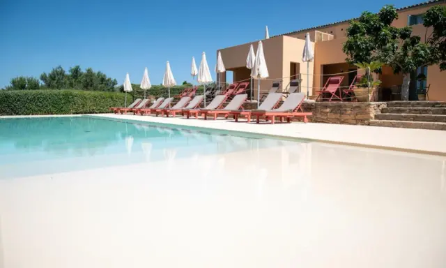 Agriturismi con piscina: lettini prendisole e ombrelloni invitano al relax in un contesto rurale.