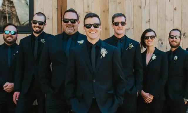 Groomsmen in matching black suits and sunglasses, showcasing stylish black suit ideas for a wedding party.
