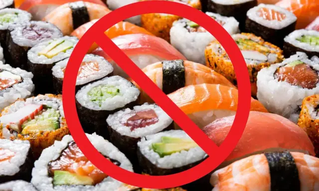 Rotes Verbotsschild über Sushi und Maki-Rollen. Achtung: verbotene Lebensmittel Schwangerschaft.