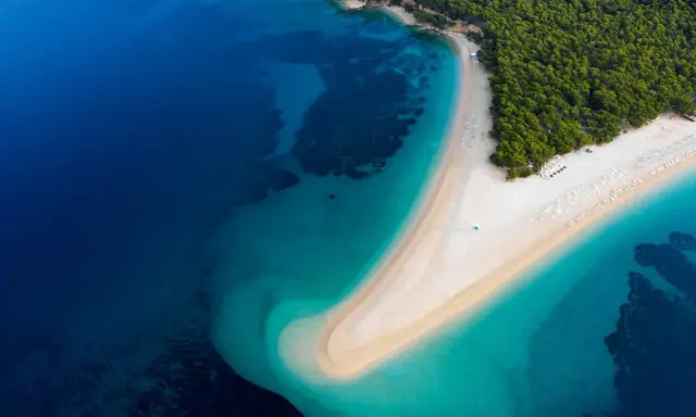 Widok z lotu ptaka na Zlatni Rat w Chorwacji. Plaże otoczone turkusowym morzem i zielonym lasem.