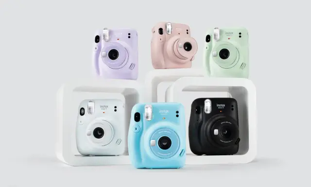 Pięć aparatów Instax Mini 11 w różnych kolorach: fioletowym, różowym, zielonym, białym, niebieskim i czarnym.