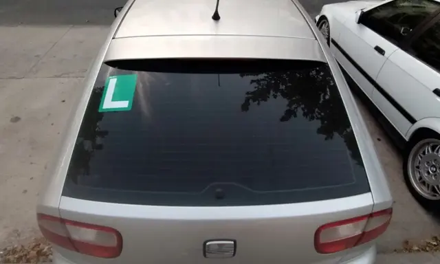 El coche plateado tiene una L verde en el lado izquierdo de la ventana trasera, indicando que el conductor está aprendiendo.