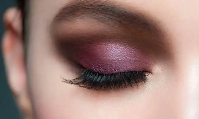 Maquillaje de ojos con sombra morada brillante y pestañas largas, ideal para realzar la mirada en párpados caídos.