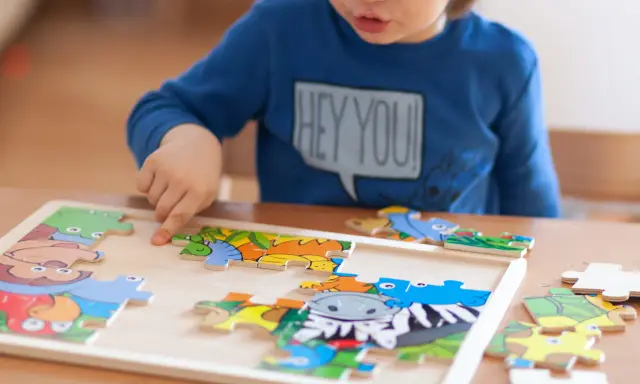 Chłopiec układa kolorowe puzzle ze zwierzątkami. Ukladanie puzzli co ćwiczy? Rozwija spostrzegawczość i zdolności manualne.