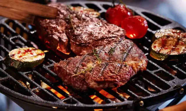 Un délicieux barbecue hivernal avec des steaks juteux, des tomates cerises et des courgettes grillées sur un feu vif.