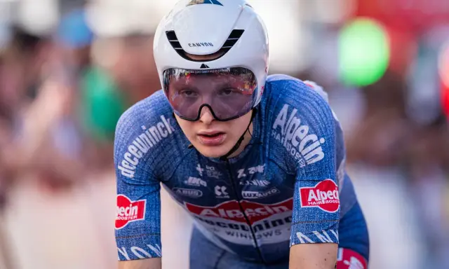 Juri Hollmann im Zeitfahr-Outfit, konzentriert auf der Strecke. Das blaue Trikot mit Alpecin-Logo und die aerodynamische Kopfbedeckung sind gut erkennbar.