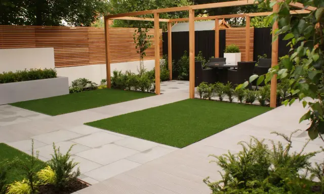 Un giardino moderno e cool con prato artificiale, pavimentazione chiara e pergolato in legno. Ideale per rilassarsi.