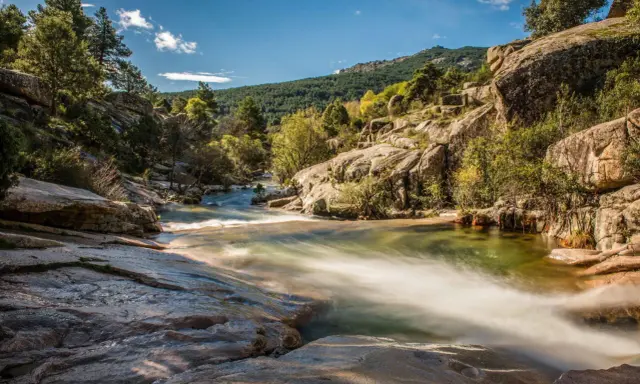 Río serpenteante entre rocas y vegetación, ideal para excursiones cerca de Madrid. Un paisaje natural de ensueño.