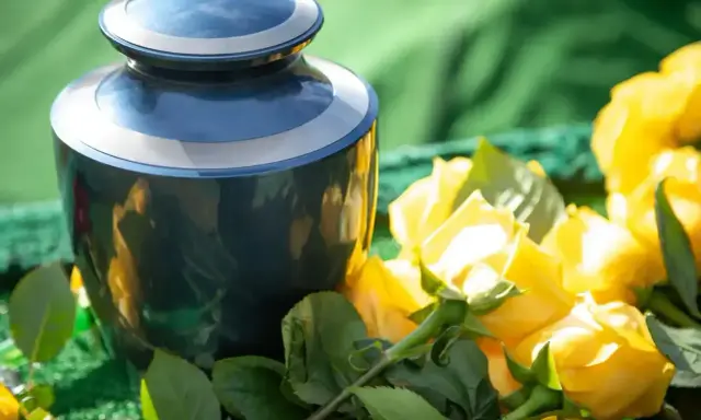 Niebieska urna i bukiet żółtych róż. Takie kwiaty na pogrzebie kolegi symbolizują pamięć i przyjaźń.