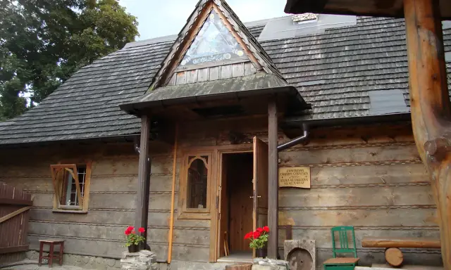 Drewniany budynek muzeum górali i zbójników z charakterystycznym trójkątnym okienkiem nad wejściem.