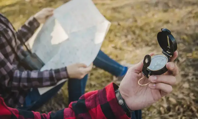 Dwie osoby sprawdzają mapę i kompas, planując swoją orientację w terenie.