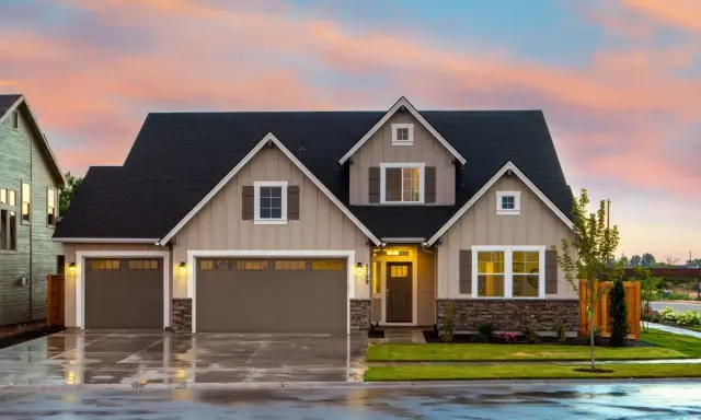Belle maison prête à finir, prix attractif. Façade beige, toit noir, garage double, jardin verdoyant sous un ciel pastel.