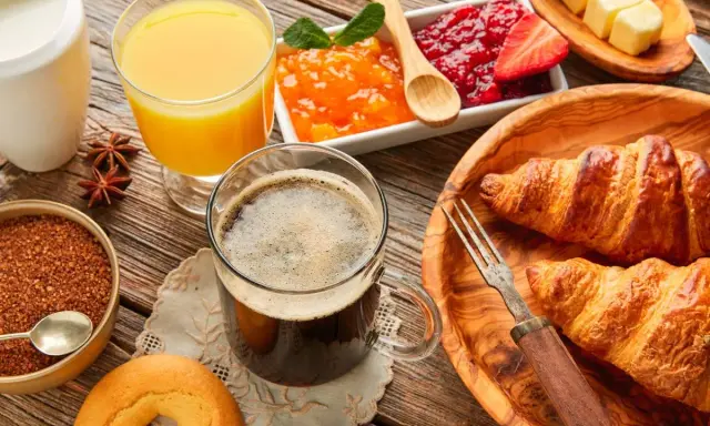 Pyszne śniadanie kontynentalne: świeże croissanty, dżemy, masło, sok pomarańczowy i kawa. Idealny początek dnia!