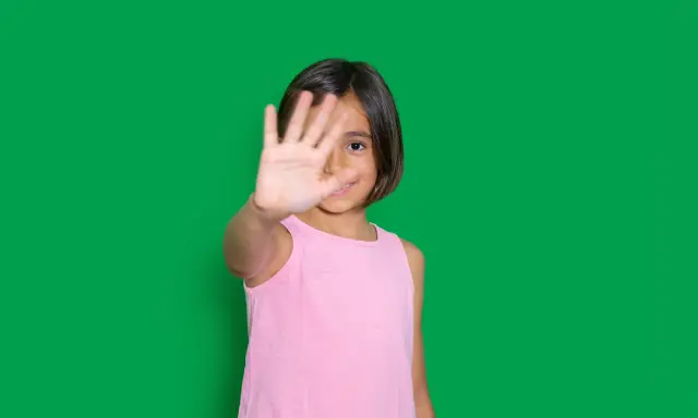 Niña de 4-5 años muestra timidez en niños, cubriendo su rostro con la mano.
