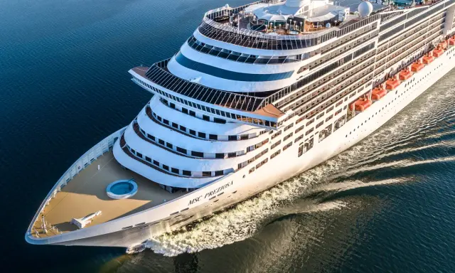 La MSC Preziosa solca il mare blu. L'equipaggio nave da crociera si prepara per un nuovo viaggio, con le scialuppe di salvataggio pronte.