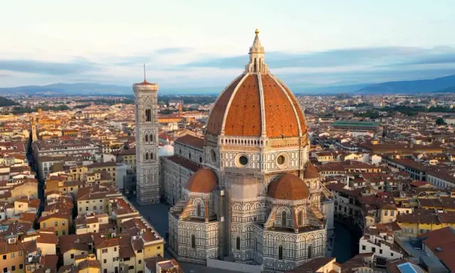 Vue aérienne de la **cattedrale Santa Maria** del Fiore et de son campanile, dominant les toits de Florence au lever du soleil.