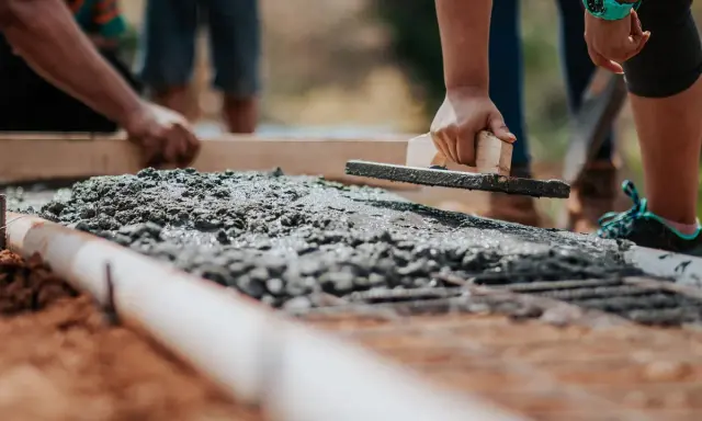 Dłoń wyrównująca świeży beton kielnią na budowie.