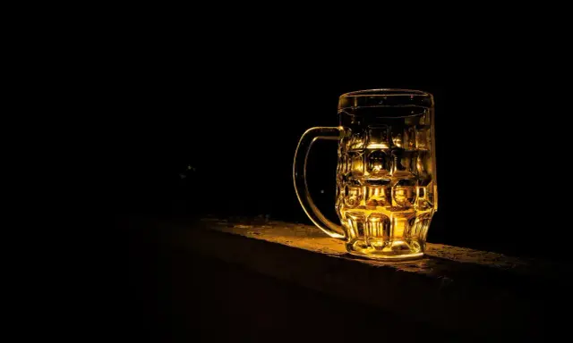 Szklanka piwa Kozel Černý, złociste światło odbija się w jej ściankach.