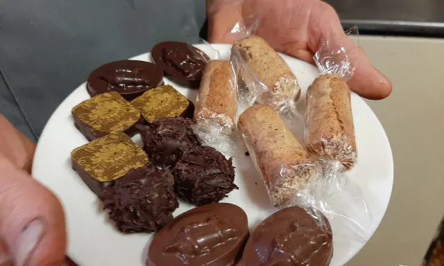 Assortiment de chocolats et biscuits, dont une spécialité d'Alençon, présentés sur une assiette blanche.