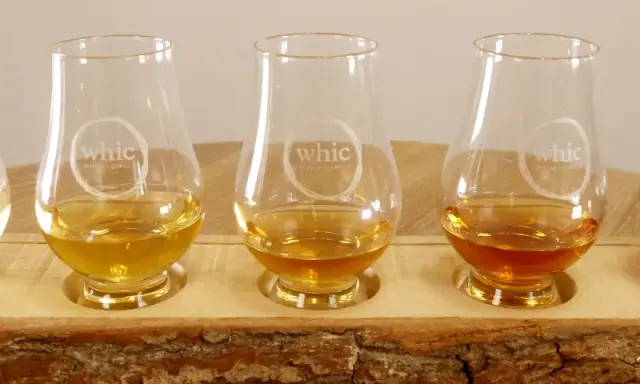 Fünf Gläser mit unterschiedlichen Farben von **whiskey ohne farbstoff** stehen auf einem Holzbrett.