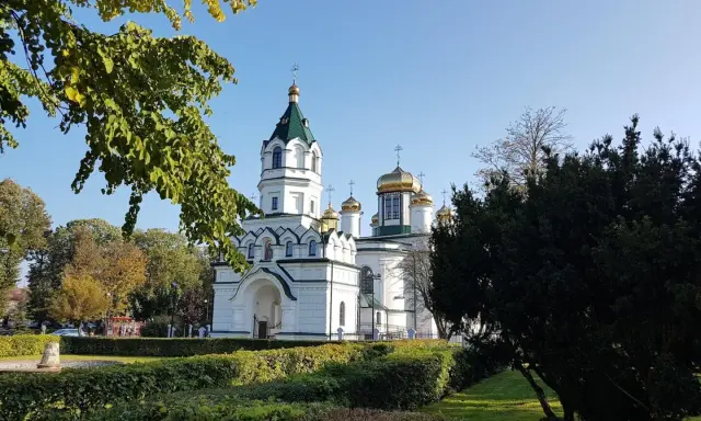 Biała cerkiew ze złotymi kopułami, otoczona zielenią. Piękny widok na szlak tatarski w słoneczny dzień.