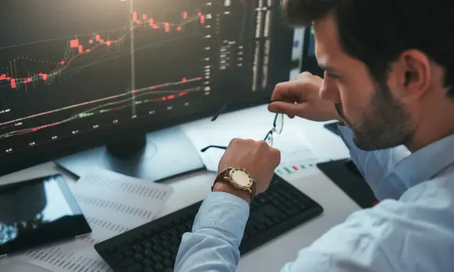 Un trader regarde sa montre, un chronophage qui le rappelle à l'ordre face aux graphiques boursiers.