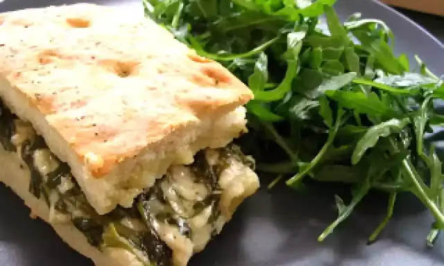Une focaccia au fromage généreusement garnie d'épinards, servie avec une salade verte fraîche.
