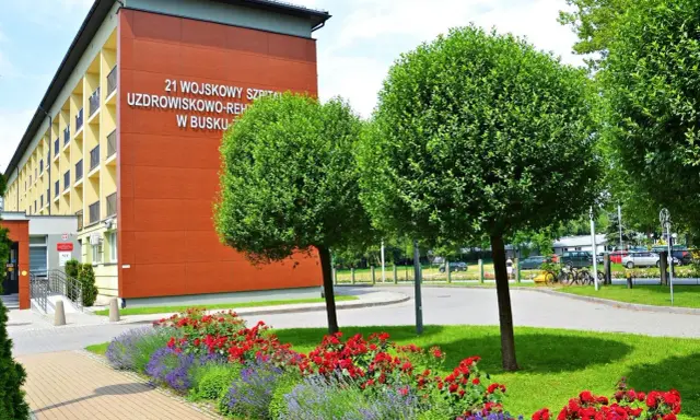 Sanatorium MSW Busko Zdrój z czerwonymi różami i lawendą w słoneczny dzień.