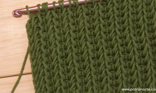 Punto tunecino con ganchillo en verde, ideal para mantas. El patrón crea un tejido denso y texturizado.