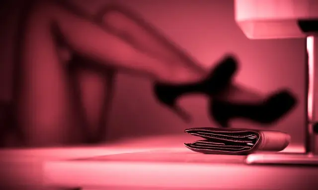 Portfel na stole, w tle niewyraźne nogi w szpilkach. To może być symbol tego, czym jest sexworking.