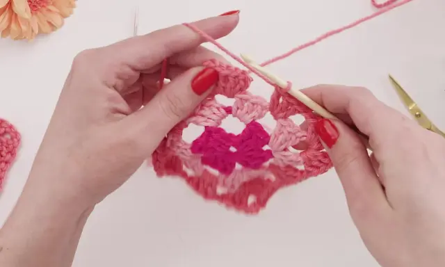 Händer virkar ett rosa virkat zigzag filt mönster med en virknål.