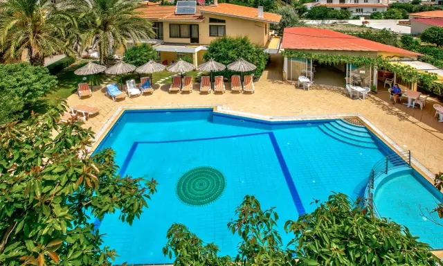 Basen hotelowy na Rodos, z leżakami i parasolami. Idealne miejsce na relaks pod słońcem.