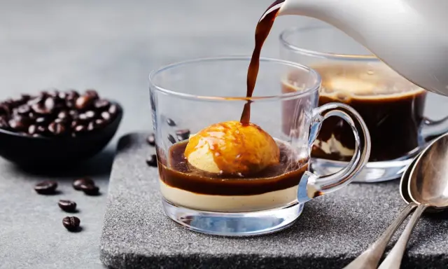 Heißer Espresso fließt über eine Eiskugel in einem Glas. Ein köstliches Cafe mit Eis, perfekt für eine süße Auszeit.