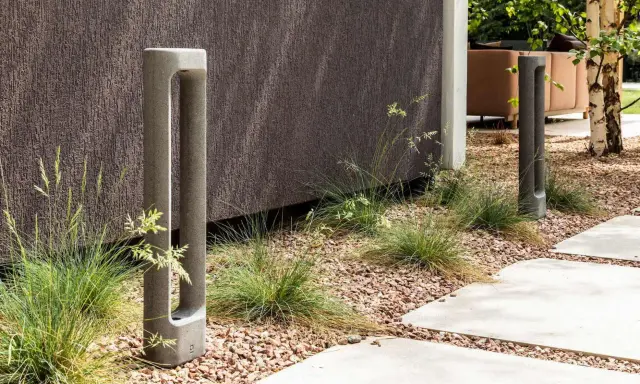 Deux bornes d'éclairage modernes en béton, bordant un chemin. L'ensemble respecte la norme éclairage lux pour un jardin contemporain.