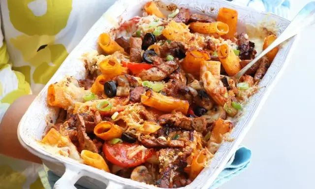 Pyszna zapiekanka z mięsem mielonym, makaronem rigatoni, oliwkami i pomidorami, posypana serem i szczypiorkiem.