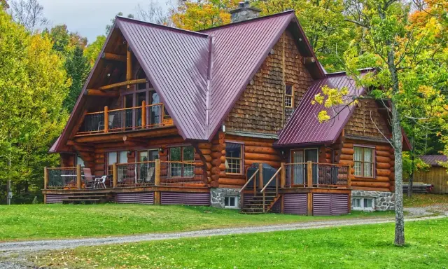 Chalet en bois rond avec toiture métallique, entouré d'arbres aux couleurs d'automne. Un exemple de développement durable bâtiment, alliant esthétique et respect de l'environnement.