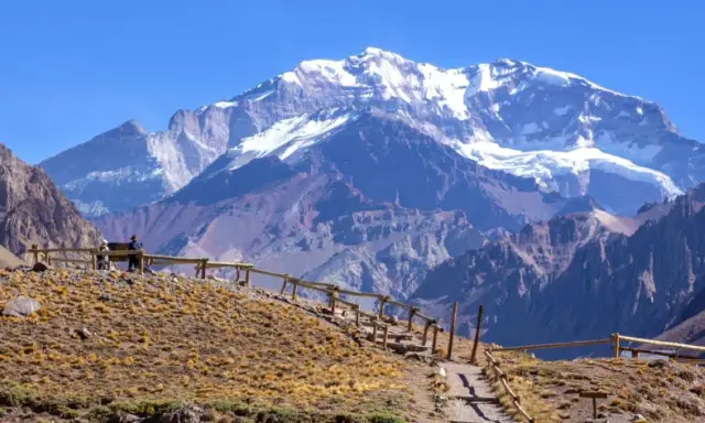 Aconcagua, najwyższy szczyt w Ameryce Południowej, góruje nad surowym krajobrazem. Ścieżka z drewnianym ogrodzeniem prowadzi na wzgórze.