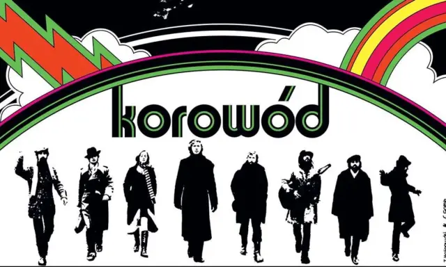 Grupa ludzi w czerni, jakby z dwóch morgi słońca, idzie pod tęczą. Napis "korowód" sugeruje, że to oni śpiewają.