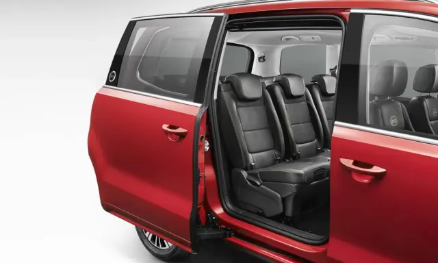 Interior de coches con puertas correderas rojas, mostrando asientos de cuero negro y detalles de costura.