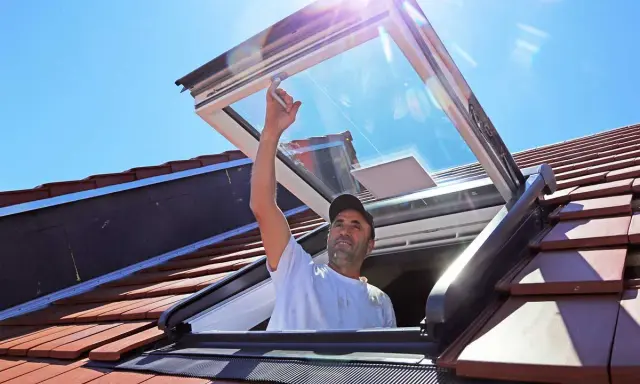 Mann installiert Dachfenster. Informieren Sie sich über Dachfenster Kosten und die Vorteile von mehr Licht.