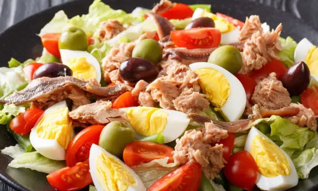 Ein bunter Nizza Salat mit Thunfisch, Ei, Tomaten, Oliven und Sardellen auf knackigem Salatbett.
