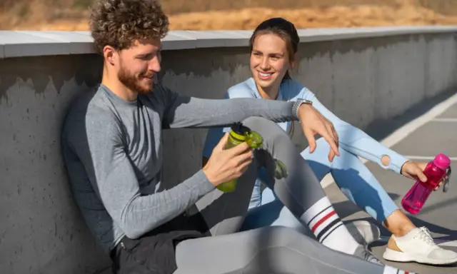 Ein Mann und eine Frau sitzen nach dem Sport und reden. Sie fragen sich, wie lange Pause nach Halbmarathon sinnvoll ist.