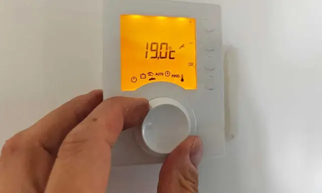 Main tenant ajuste le thermostat pour un mode confort, affichant 19.0°C.