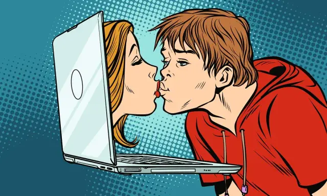 Chłopak i dziewczyna całują się przez ekran laptopa, symbolizując cyber sex i wirtualną bliskość.