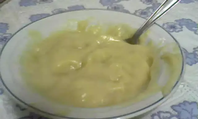 Un tazón blanco con un suave y cremoso puré de pescado, listo para ser disfrutado. Una cuchara plateada descansa en el tazón.